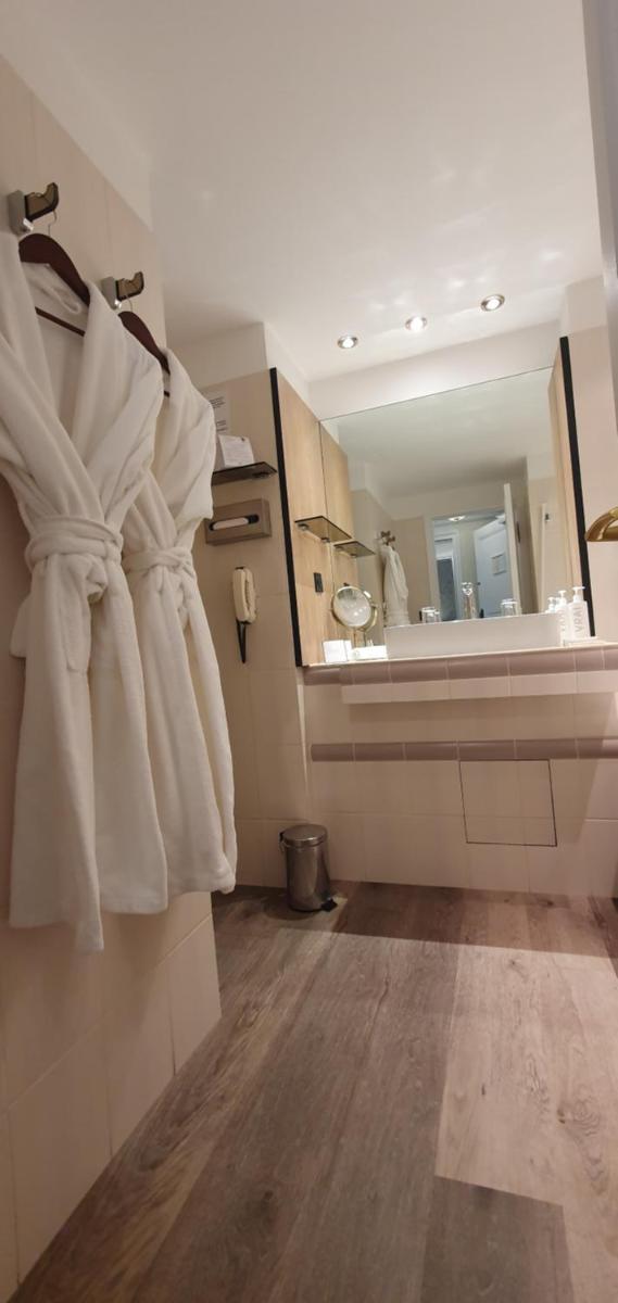 une salle de bains avec des serviettes blanches accrochées au mur dans l'établissement Demeures & Châteaux - Hôtel Greuze & Spa Tournus, à Tournus 33 autres photos
