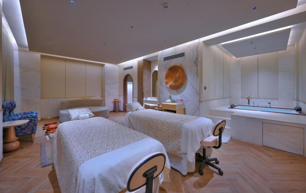 a bedroom with two beds and a kitchen with a sink at Taj Agra in Agra