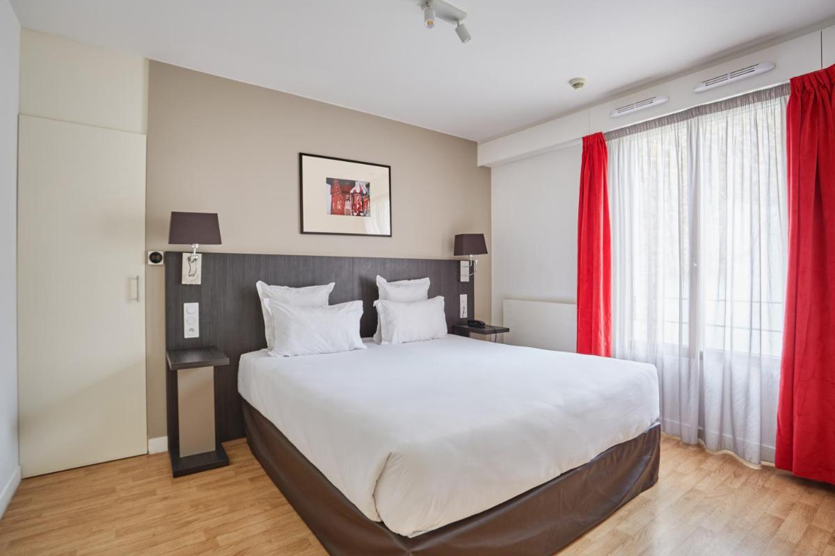 - une chambre avec un grand lit et des rideaux rouges dans l'établissement Appart Hotel Odalys City Paris Montmartre, à Paris