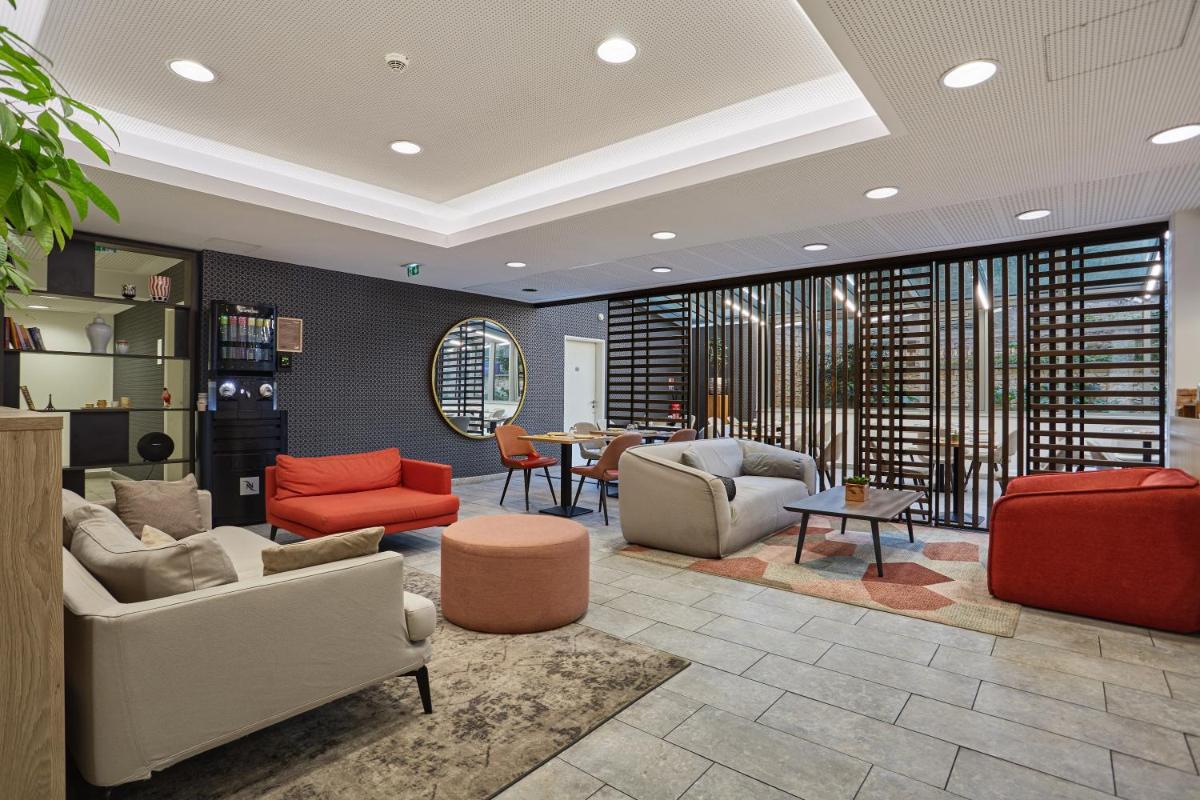 un salon avec des canapés, des chaises et une table dans l'établissement Appart Hotel Odalys City Paris Montmartre, à Paris