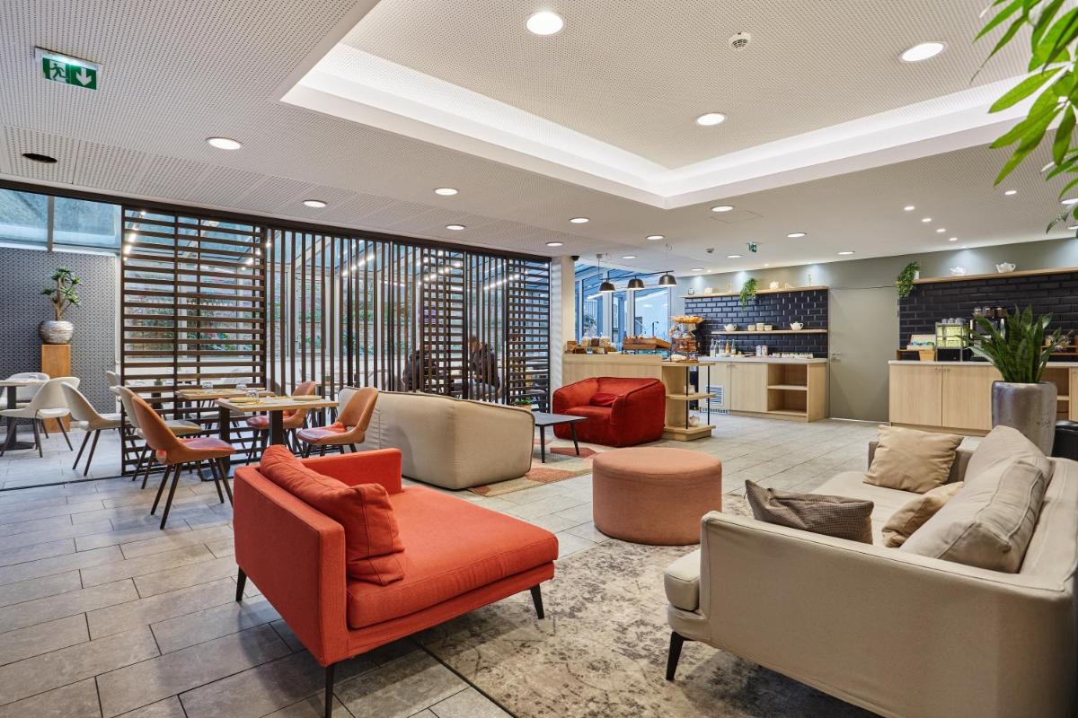 un hall avec des canapés et des chaises ainsi qu'un restaurant dans l'établissement Appart Hotel Odalys City Paris Montmartre, à Paris