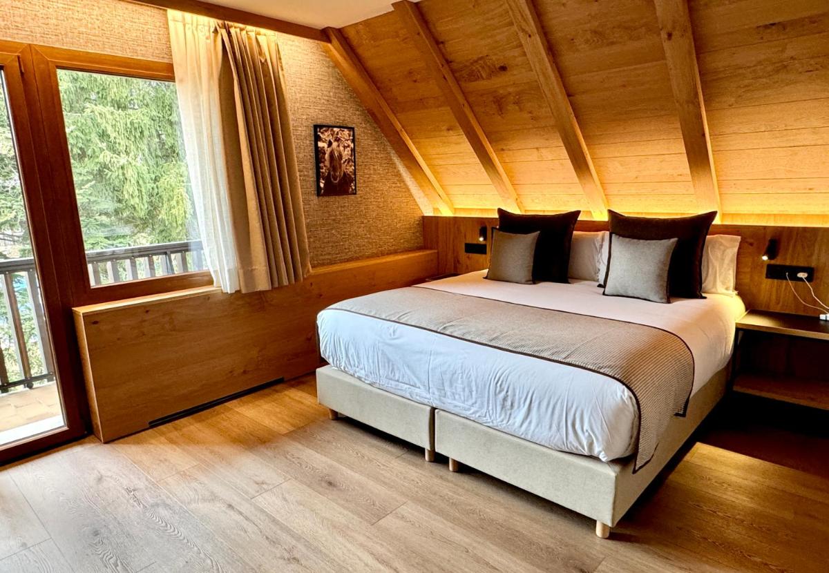 1 dormitorio con 1 cama grande en una habitación con ventanas en Hotel Petit Lacreu, en Salardú