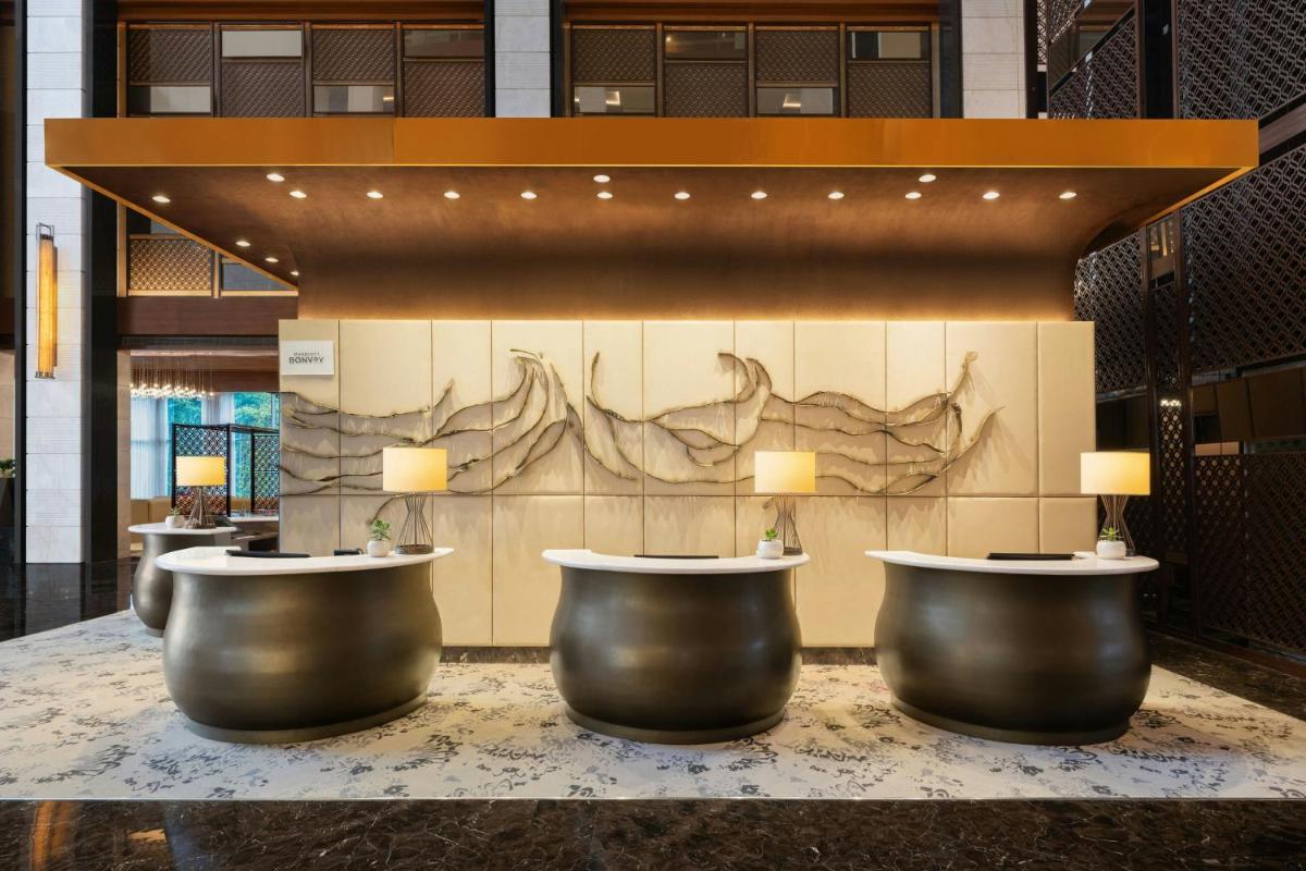 a lobby with a row ofools in front of a wall at Sheraton Hyderabad Hotel in Hyderabad