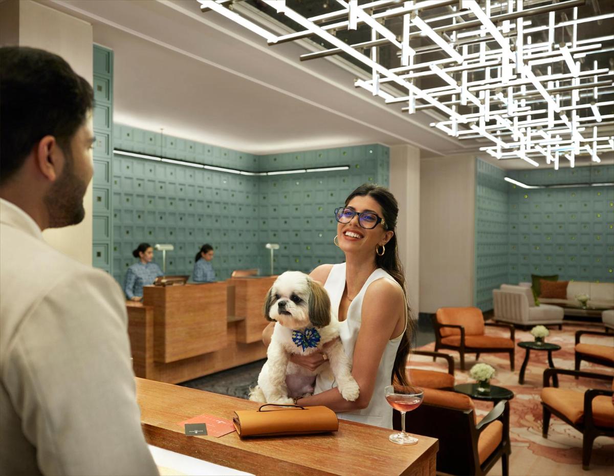a woman holding a small white dog at a table at Four Seasons Hotel Mumbai in Mumbai