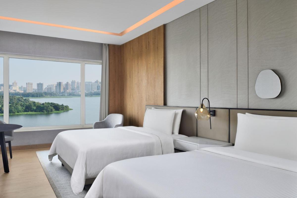 a hotel room with two beds and a window at The Westin Mumbai Powai Lake in Mumbai