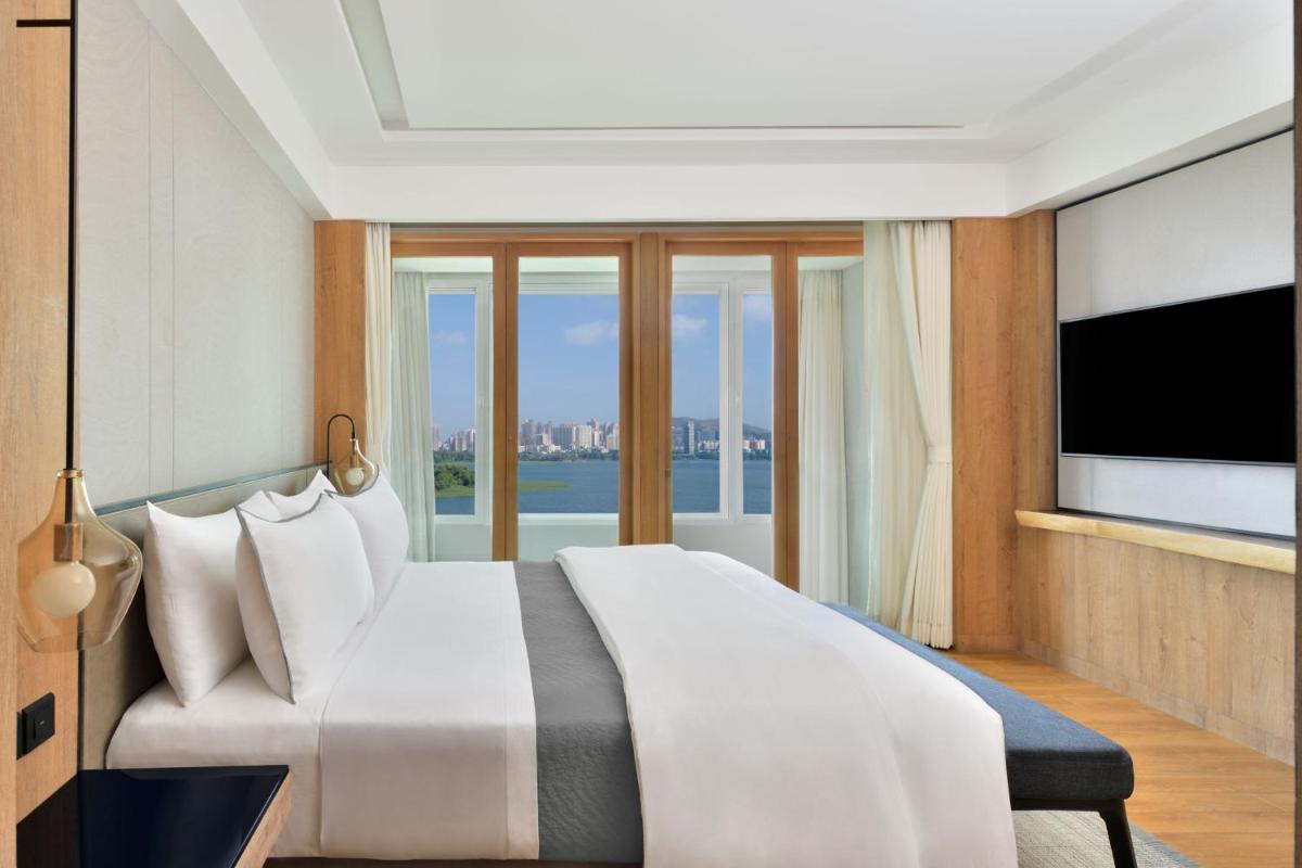 a bedroom with a large bed and a television at The Westin Mumbai Powai Lake in Mumbai