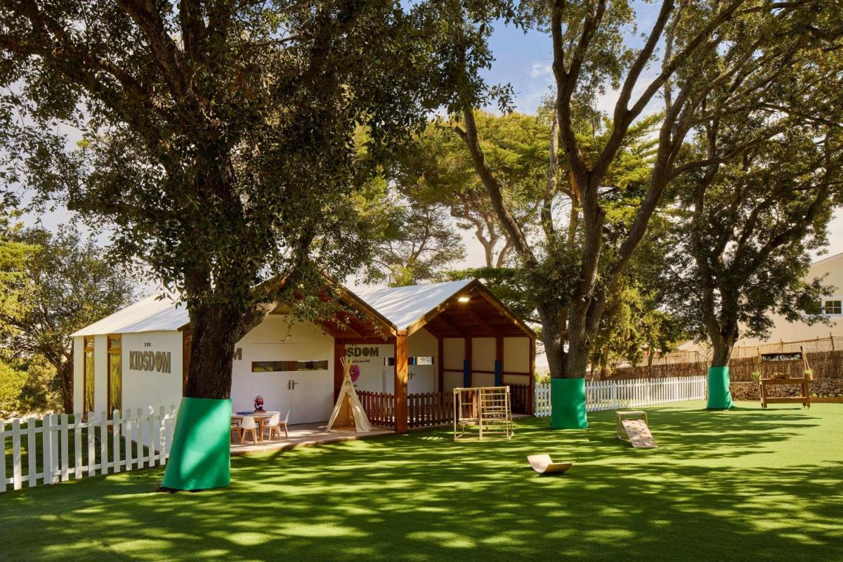 Tienda en un patio con árboles y césped en Meliá Cala Galdana, en Cala Galdana