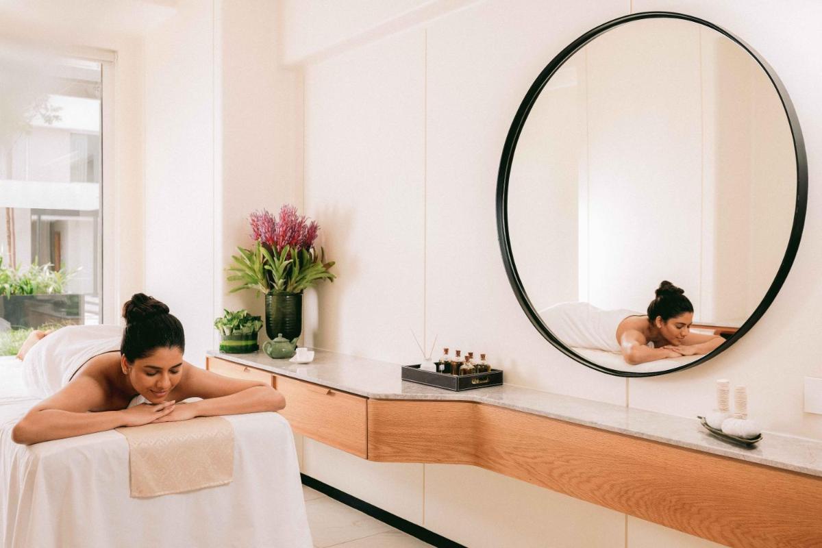 a woman laying in a bath room with a mirror at Pullman Chennai Anna Salai - Premium Brand By Accor in Chennai