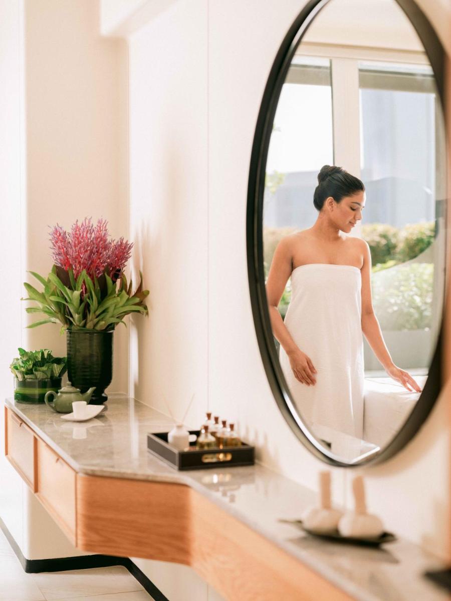 a woman in a white dress standing in front of a mirror at Pullman Chennai Anna Salai - Premium Brand By Accor in Chennai