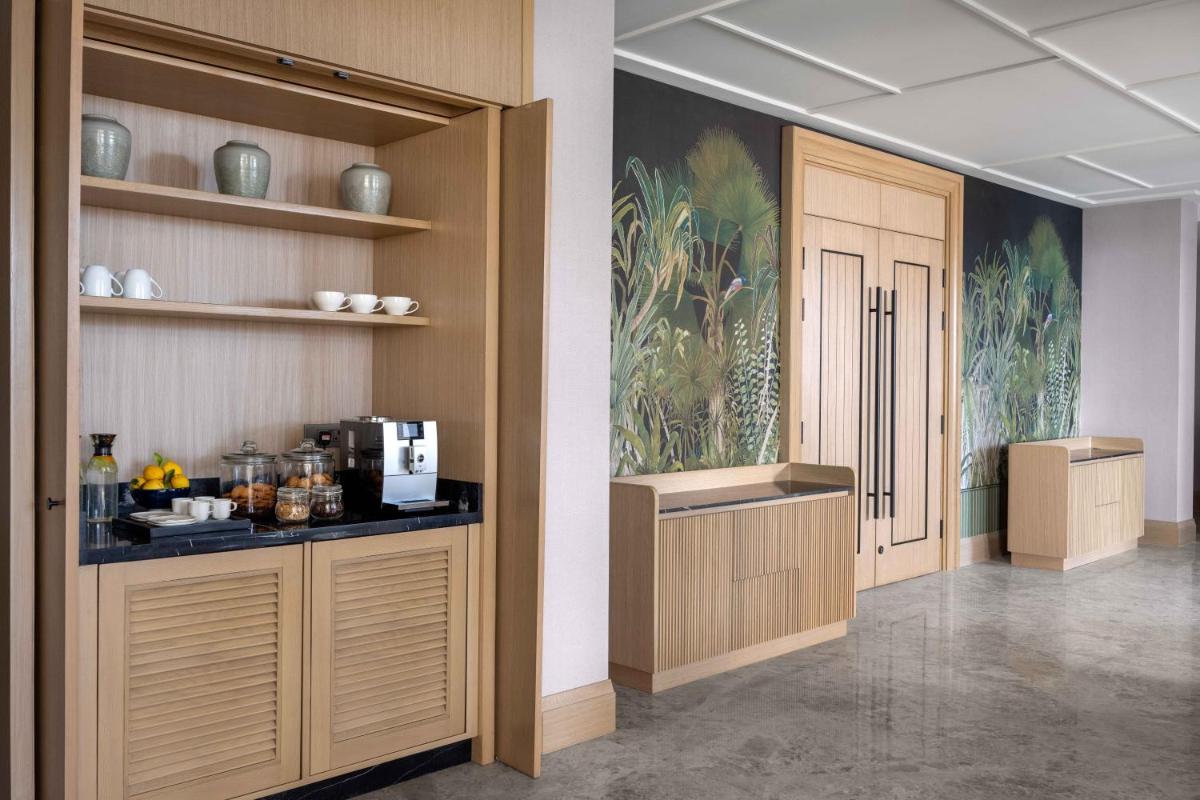 a room with a kitchen with wooden cabinets and shelves at Pullman Chennai Anna Salai - Premium Brand By Accor in Chennai