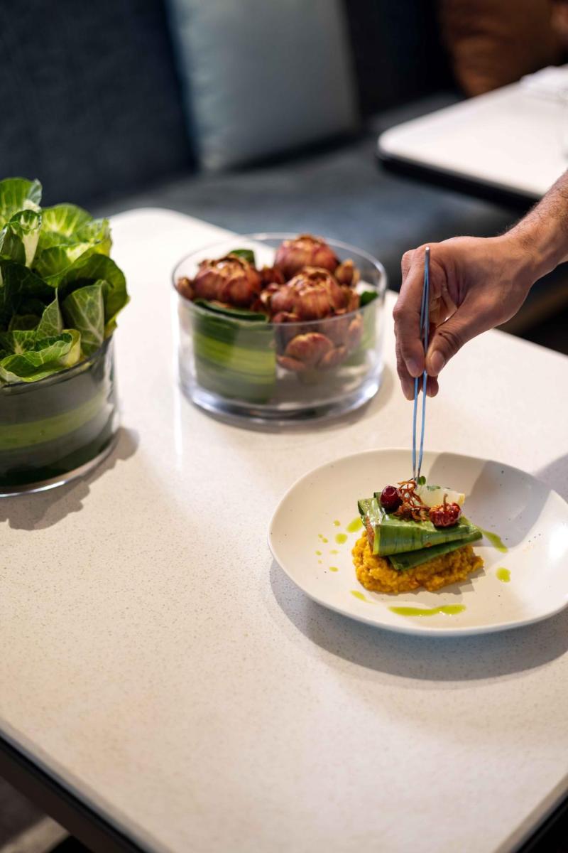 a person eating a plate of food on a counter at Pullman Chennai Anna Salai - Premium Brand By Accor in Chennai