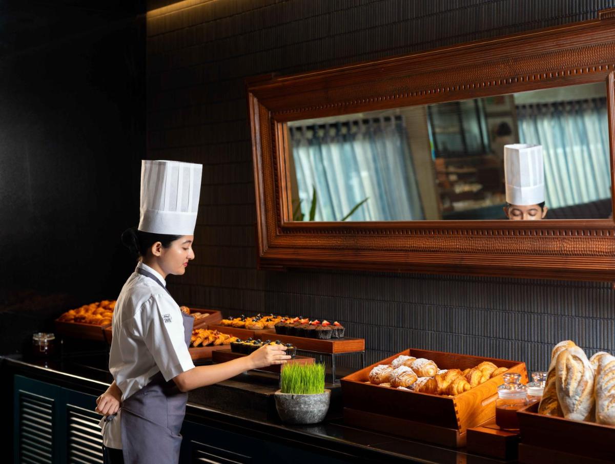 a woman standing in a kitchen preparing food at Pullman Chennai Anna Salai - Premium Brand By Accor in Chennai