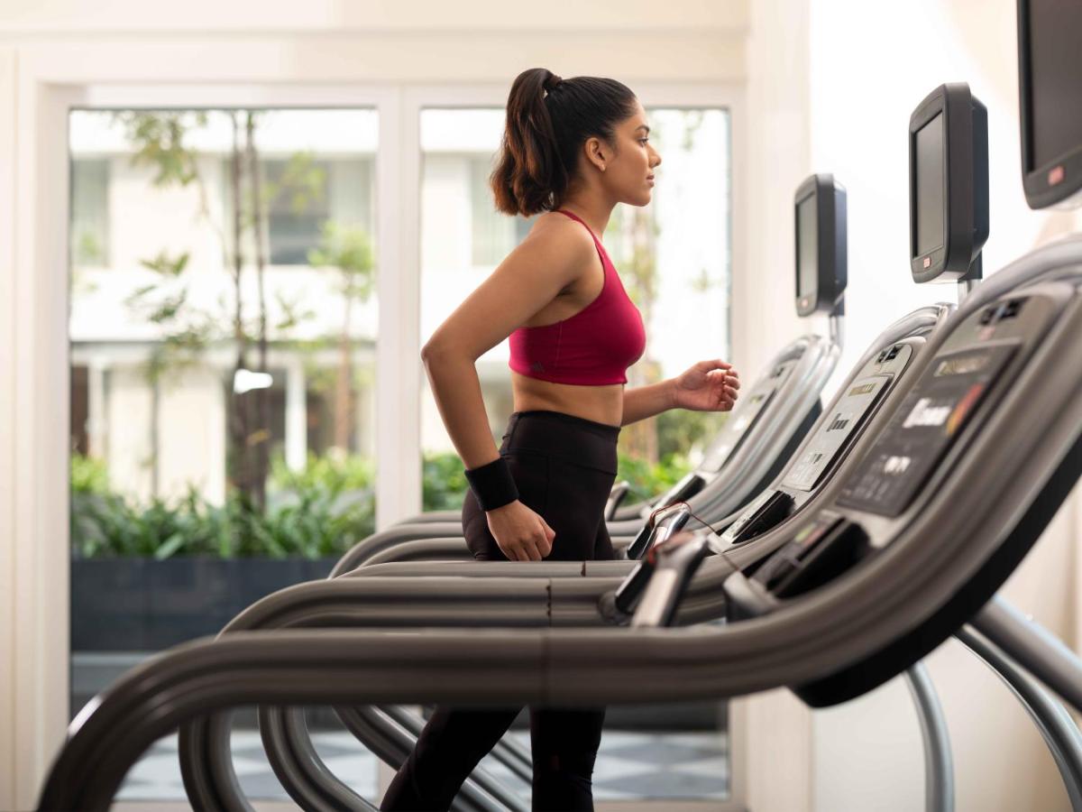a woman running on a treadmill in a gym at Pullman Chennai Anna Salai - Premium Brand By Accor in Chennai