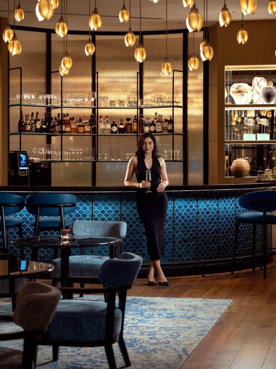 a woman standing in front of a bar at Pullman Chennai Anna Salai - Premium Brand By Accor in Chennai