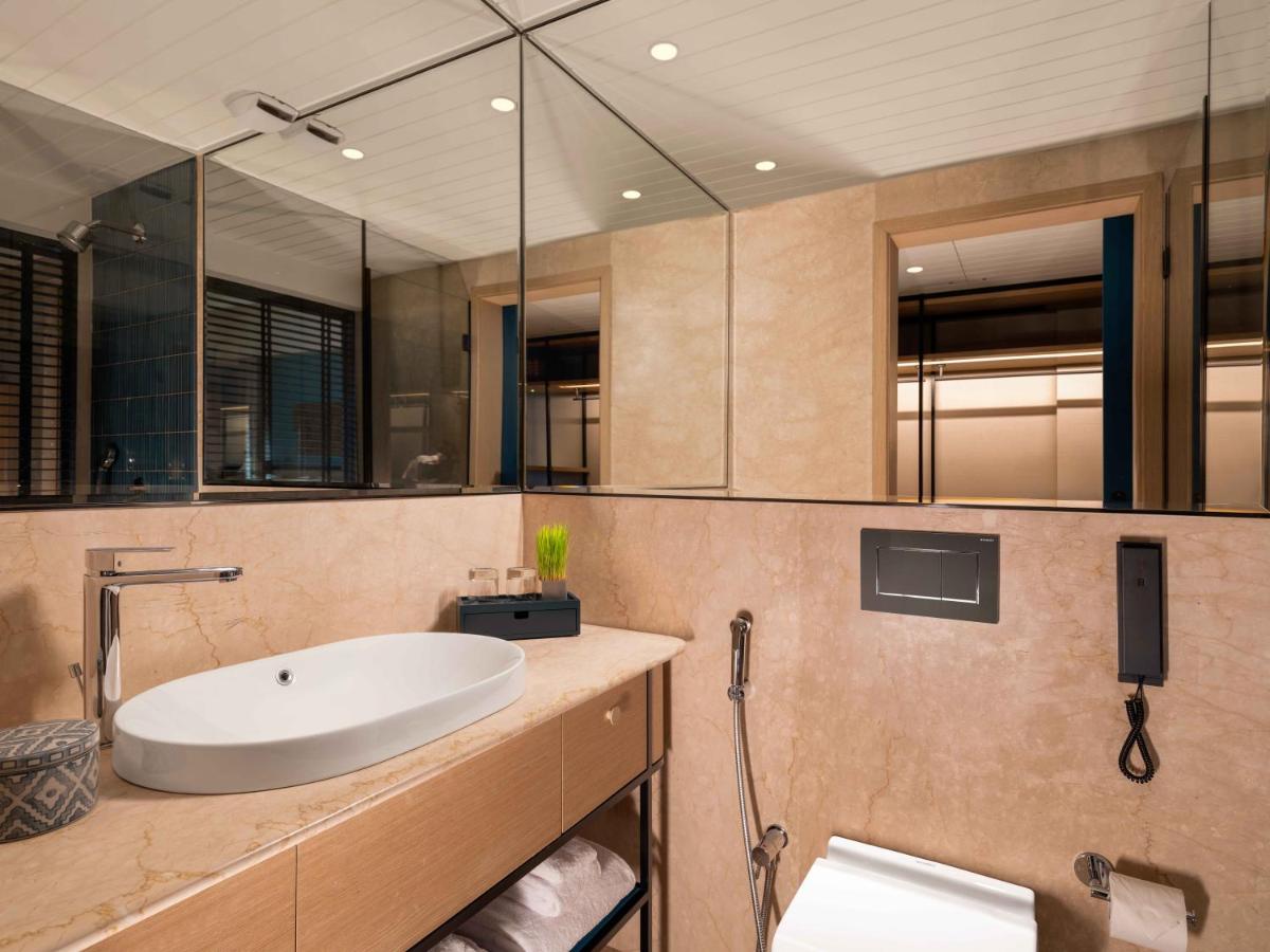 a bathroom with a sink and a large mirror at Pullman Chennai Anna Salai - Premium Brand By Accor in Chennai