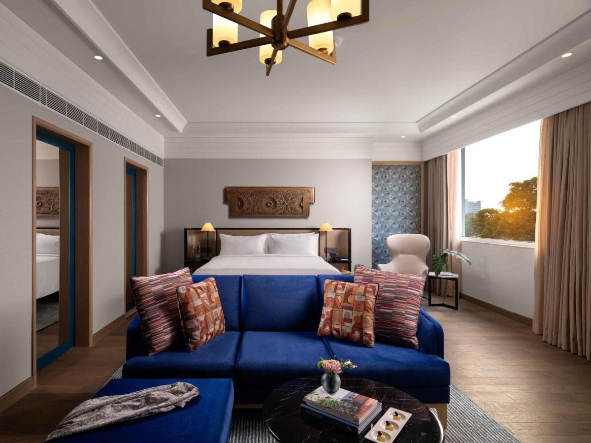 a hotel room with a bed and a blue couch at Pullman Chennai Anna Salai - Premium Brand By Accor in Chennai