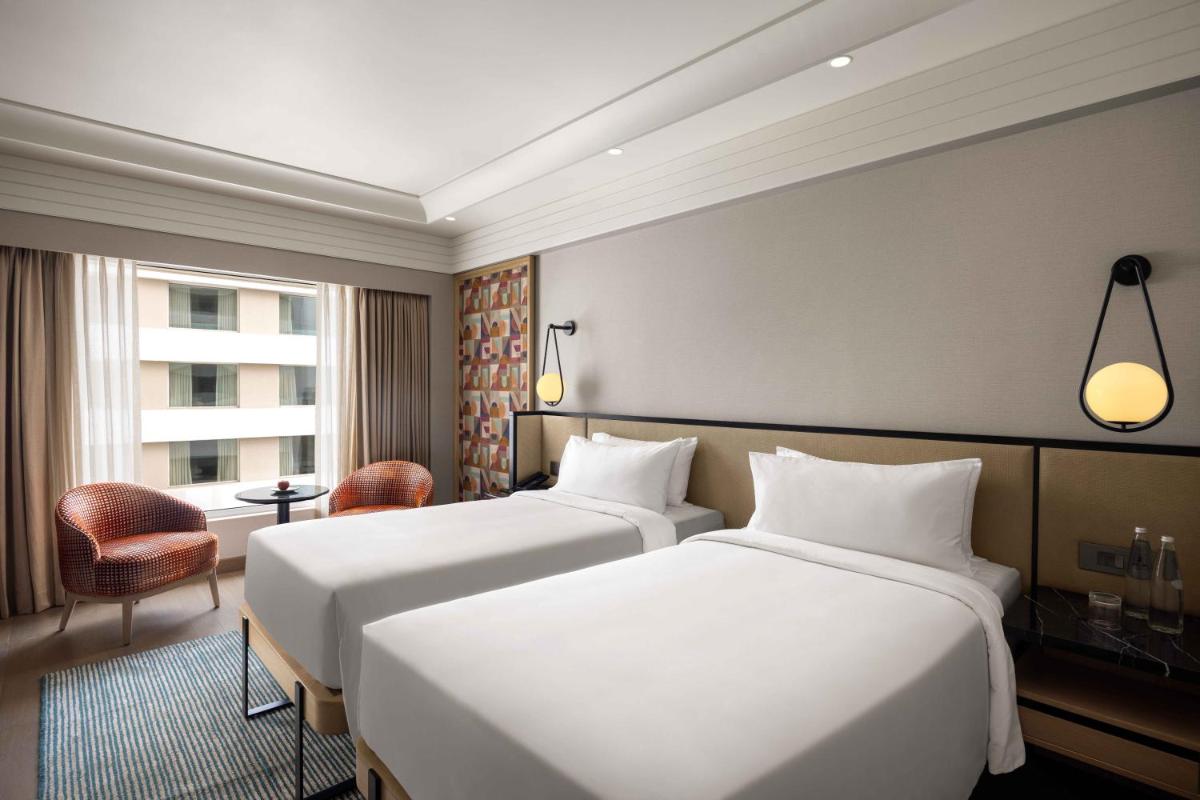 a hotel room with two beds and a window at Pullman Chennai Anna Salai - Premium Brand By Accor in Chennai