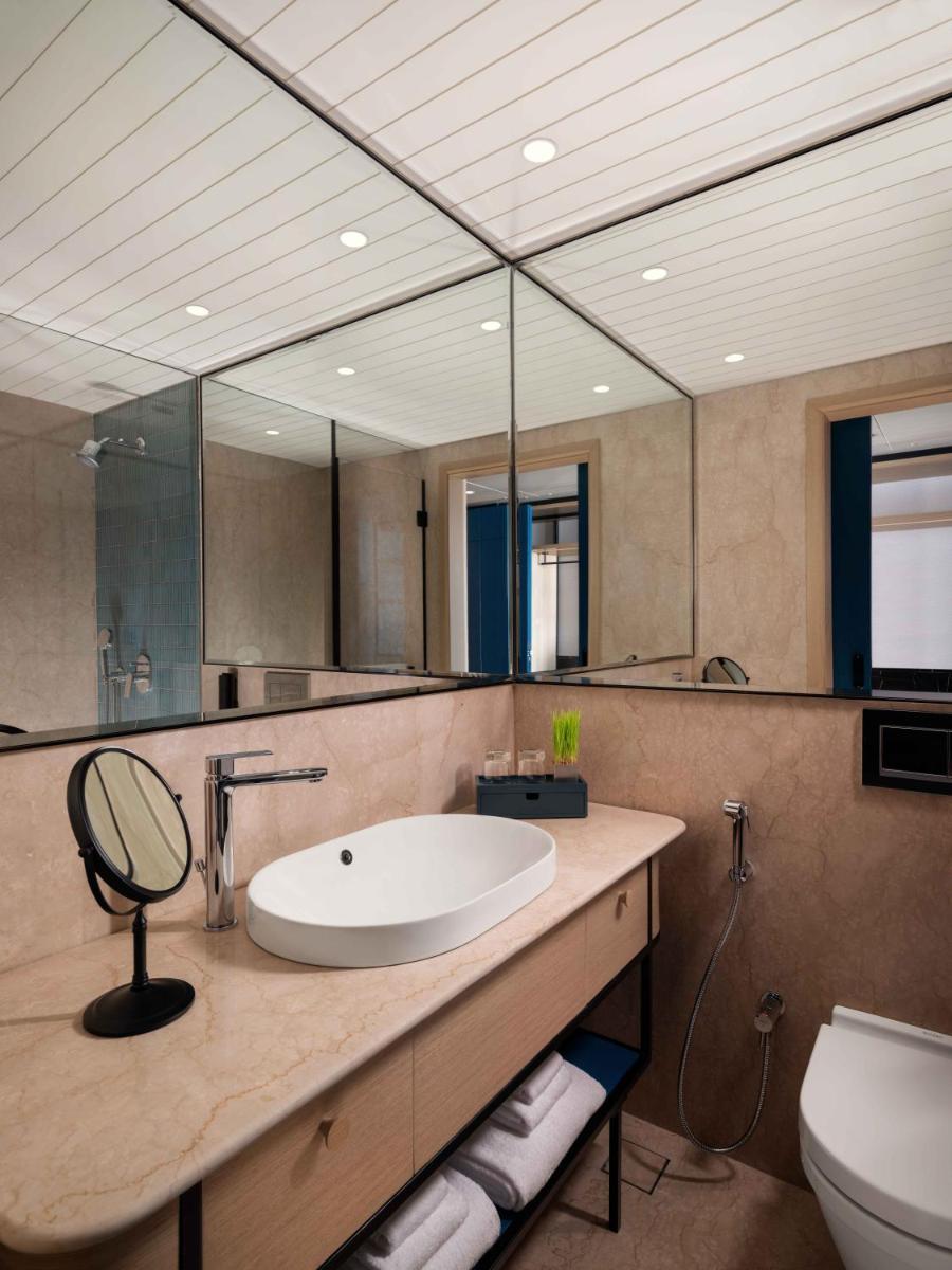 a bathroom with a sink and a toilet and a mirror at Pullman Chennai Anna Salai - Premium Brand By Accor in Chennai