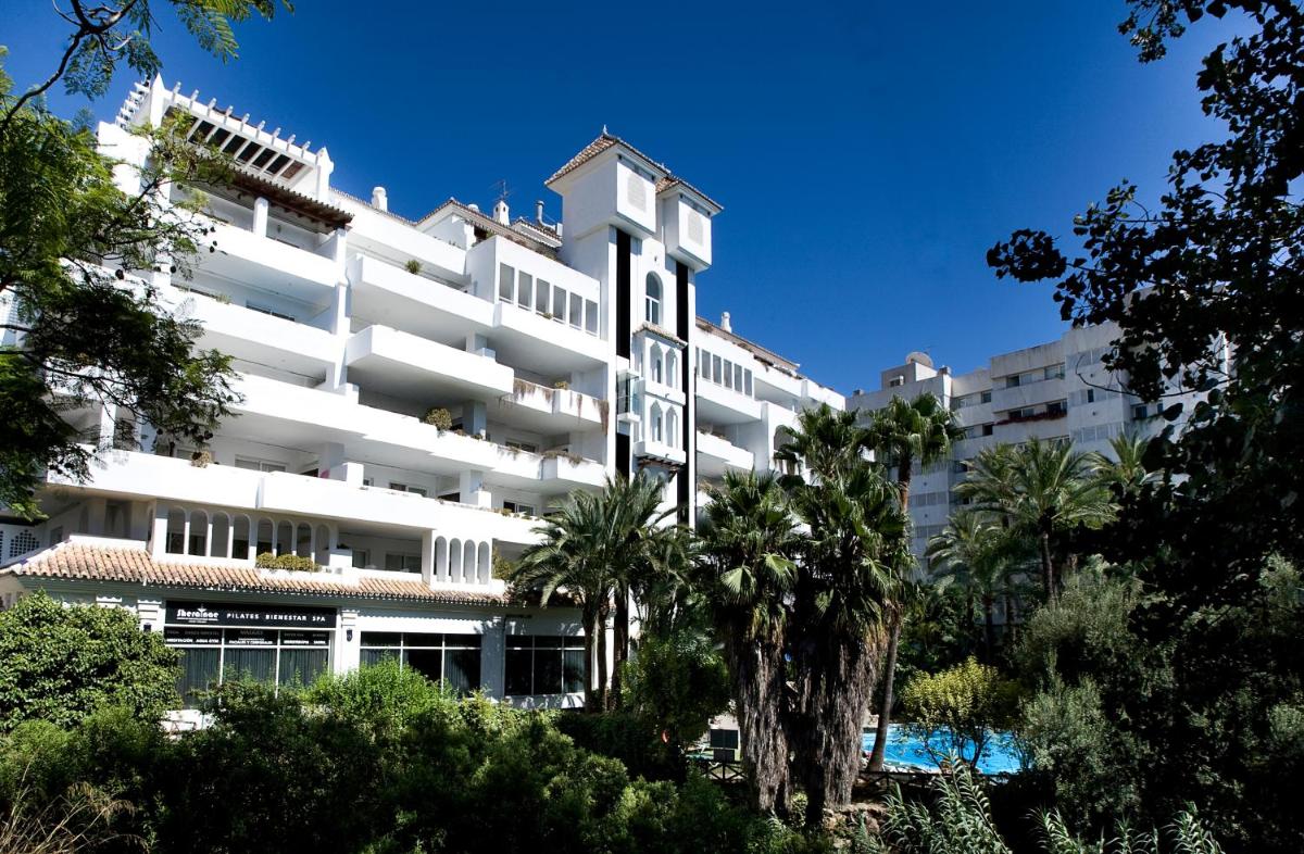 Un gran edificio blanco con árboles delante. en Aparthotel Monarque Sultán, en Marbella