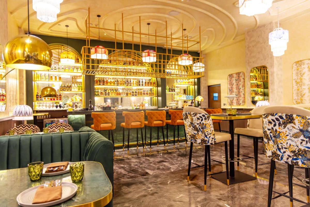 a restaurant with a green couch and a bar at DoubleTree Suites by Hilton Bengaluru Outer Ring Road in Bengaluru