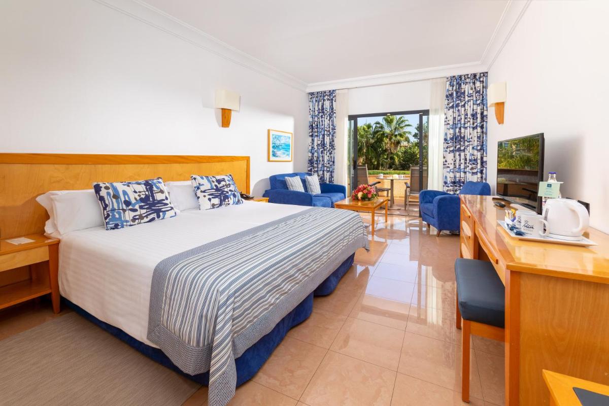 Una habitación de hotel con una cama y una sala de estar. en MUR Faro Jandia Fuerteventura & Spa, en Morro del Jable