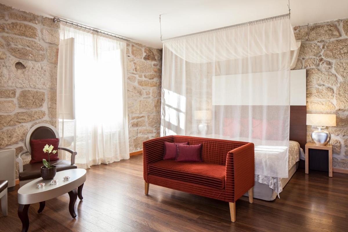 uma sala de estar com uma cadeira vermelha e uma cama em Casas Novas Countryside Hotel Spa & Events em Chaves
