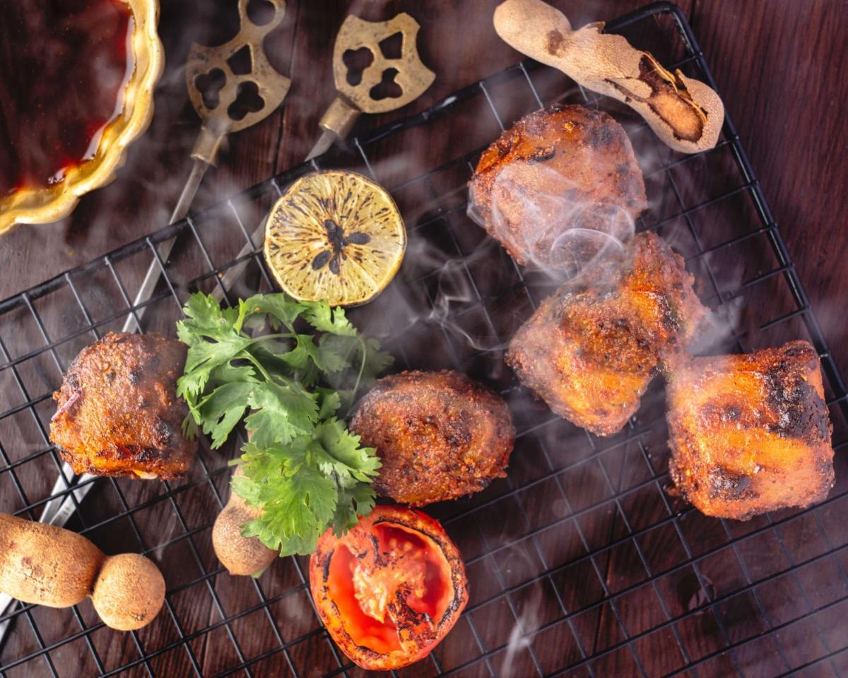 a grill with meat and vegetables and a lemon at Radisson Blu Plaza Delhi Airport in New Delhi a grill with meat and vegetables and a lemon at Radisson Blu Plaza Delhi Airport in New Delhi