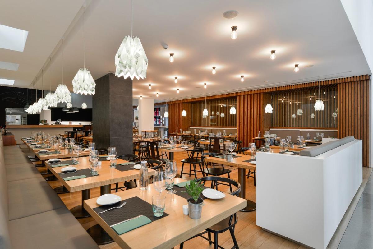 um restaurante com mesas e cadeiras de madeira e lustres em Inspira Liberdade Boutique Hotel em Lisboa