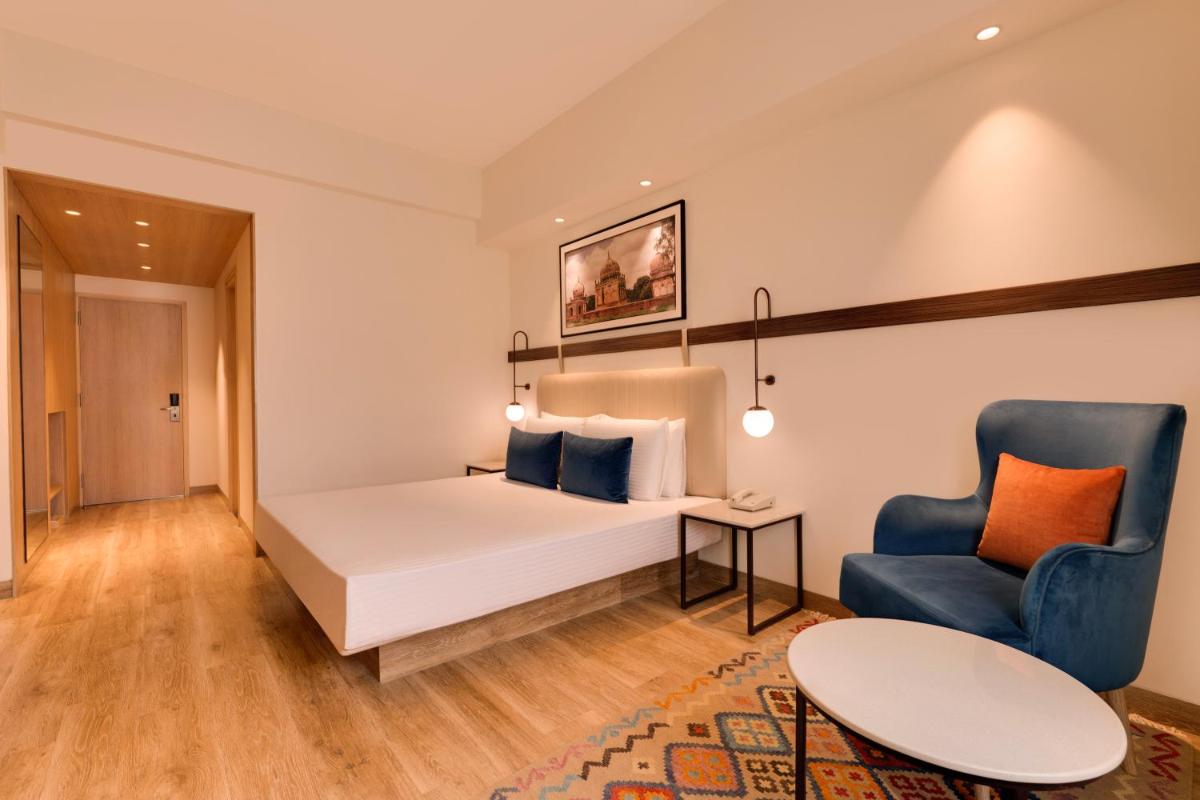 a hotel room with a bed and a blue chair at Lemon Tree Premier Hitec City Hyderabad in Hyderabad