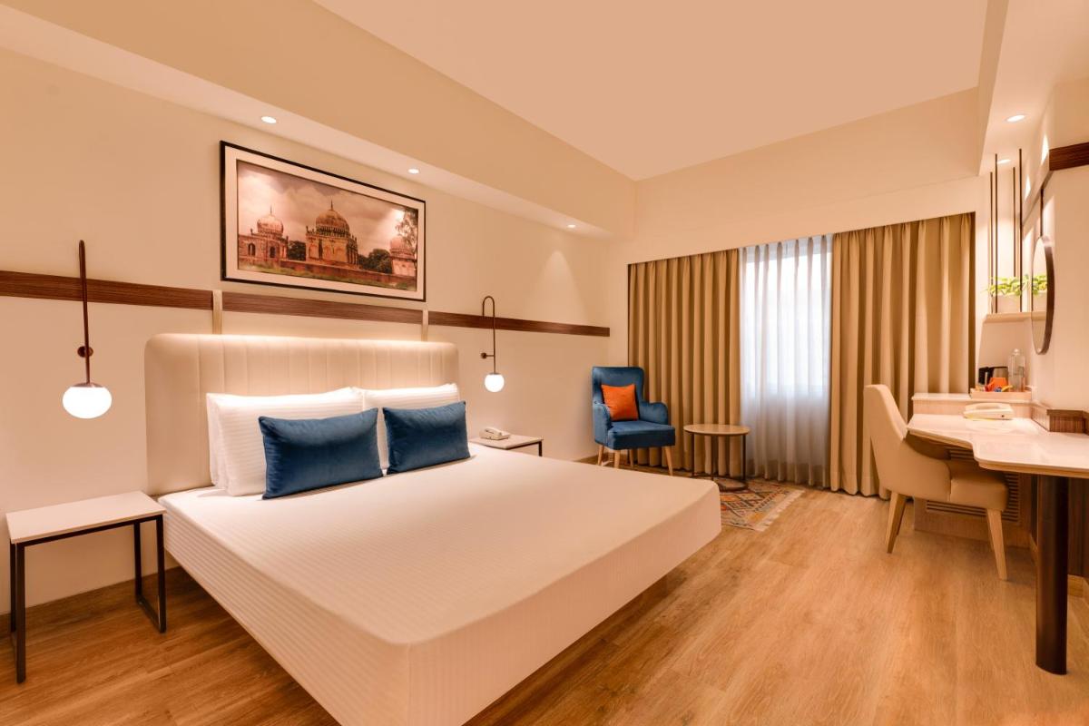 a hotel room with a bed and a desk at Lemon Tree Premier Hitec City Hyderabad in Hyderabad