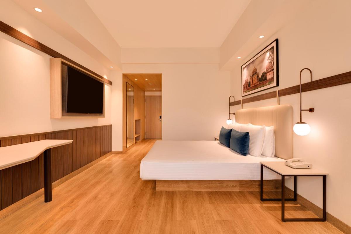 a hotel room with a bed and a flat screen tv at Lemon Tree Premier Hitec City Hyderabad in Hyderabad
