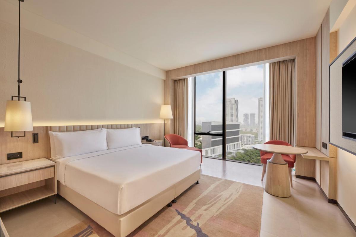 a bedroom with a white bed and a large window at Hilton Gurugram Baani City Centre in Gurgaon