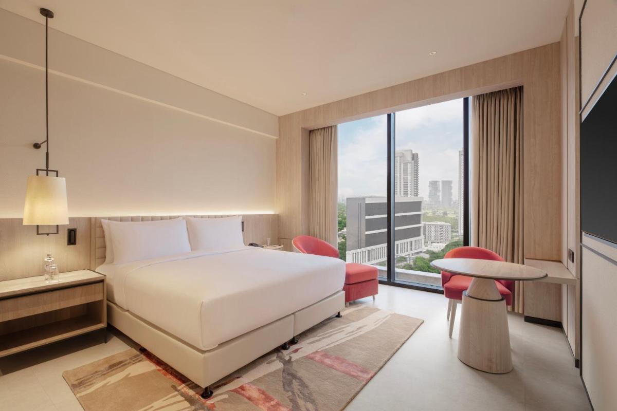 a hotel room with a bed and a large window at Hilton Gurugram Baani City Centre in Gurgaon