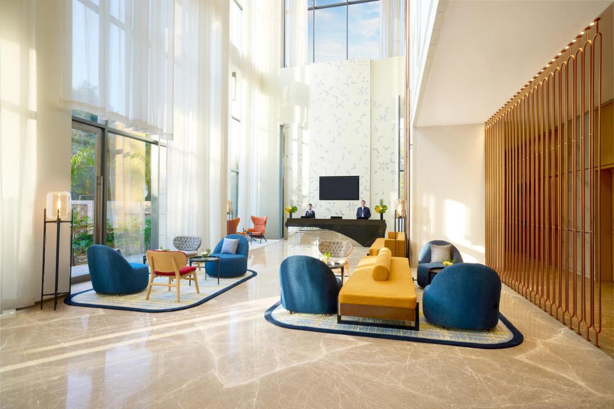 a lobby with chairs and a table and a television at Novotel New Delhi City Centre in New Delhi a lobby with chairs and a table and a television at Novotel New Delhi City Centre in New Delhi