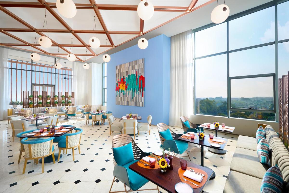 a rendering of a restaurant with tables and chairs and large windows at Novotel New Delhi City Centre in New Delhi a rendering of a restaurant with tables and chairs and large windows at Novotel New Delhi City Centre in New Delhi