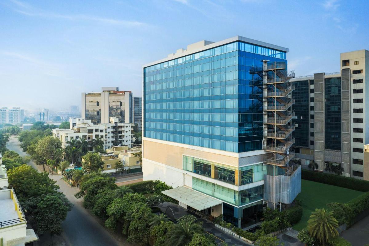 a tall glass office building in a city at Renaissance Ahmedabad Hotel in Ahmedabad