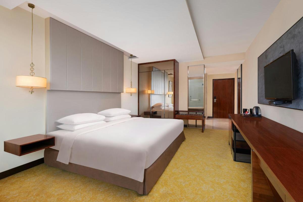 a hotel room with a bed and a flat screen tv at Renaissance Ahmedabad Hotel in Ahmedabad