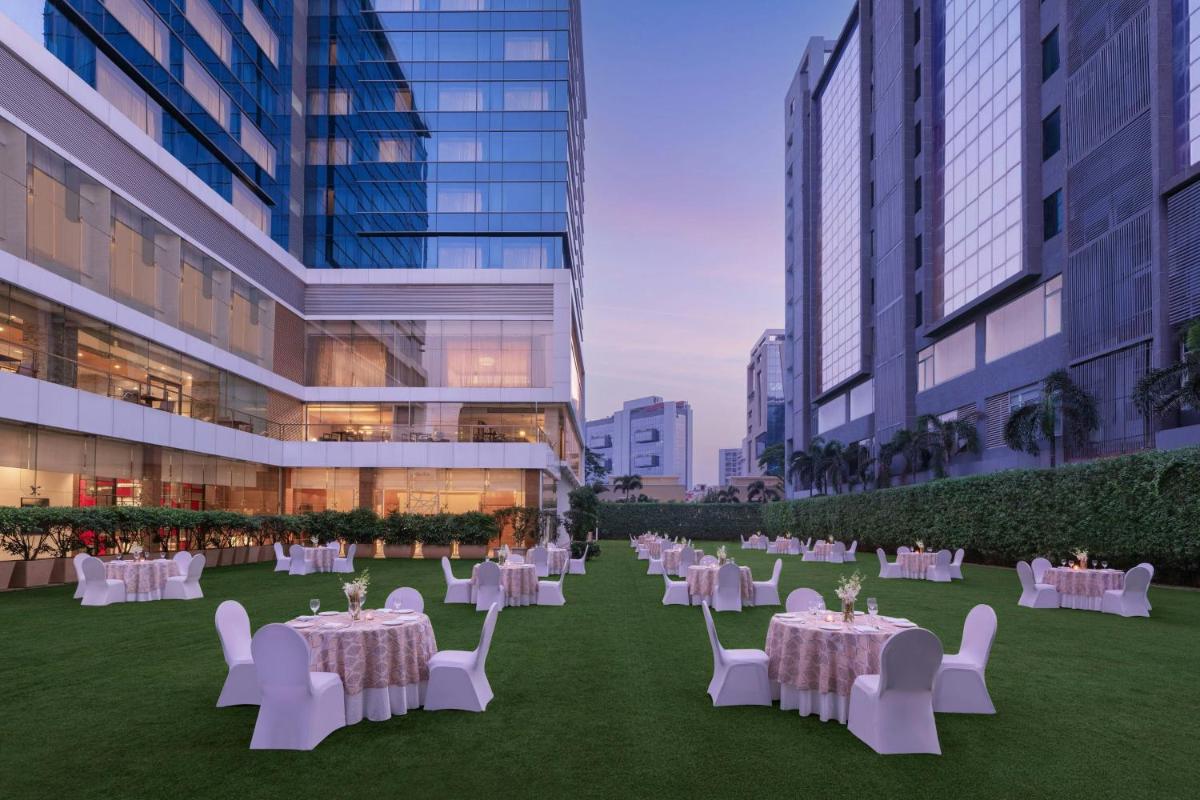 a banquet area with white tables and chairs in a building at Renaissance Ahmedabad Hotel in Ahmedabad