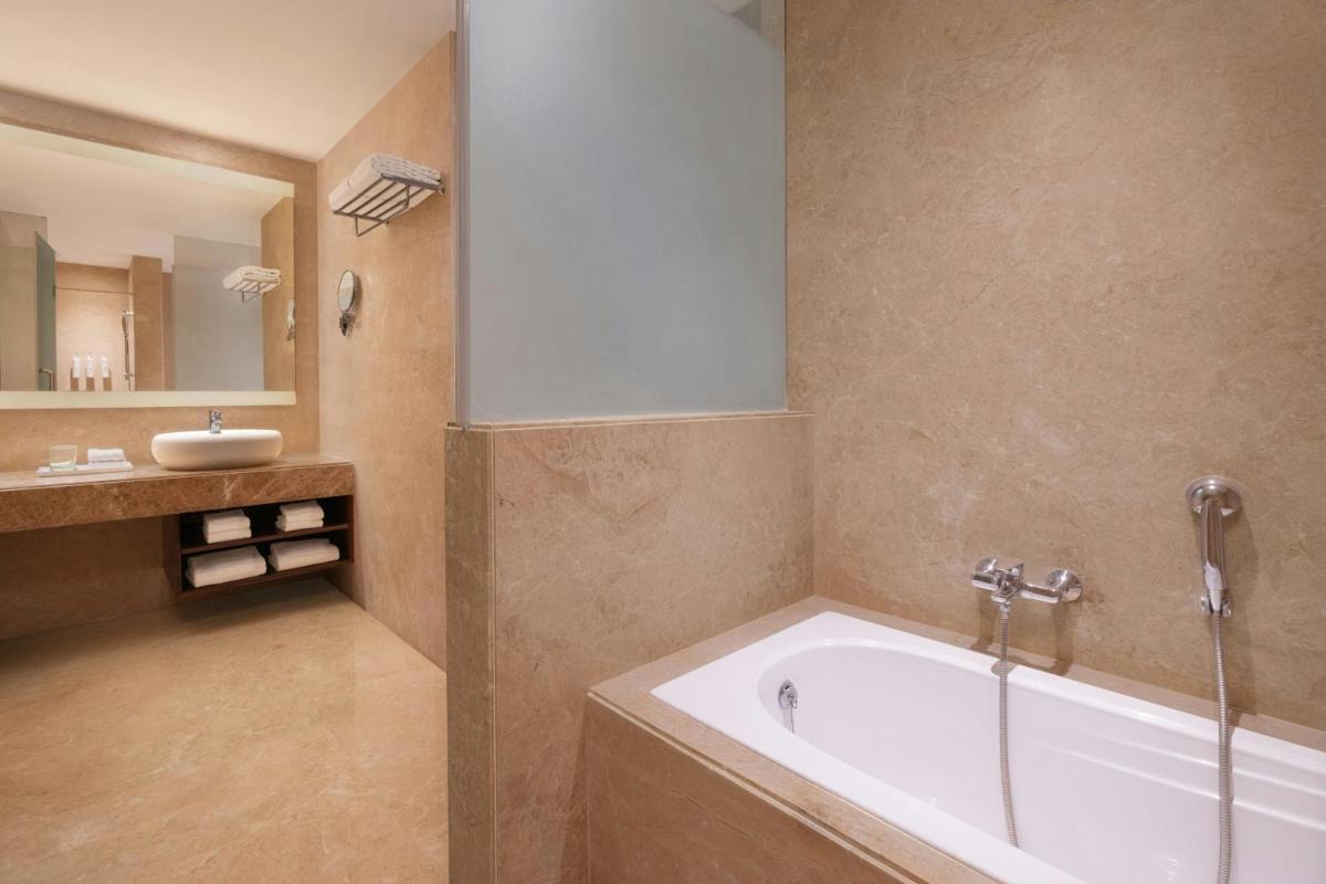 a bathroom with a bath tub and a sink at Renaissance Ahmedabad Hotel in Ahmedabad