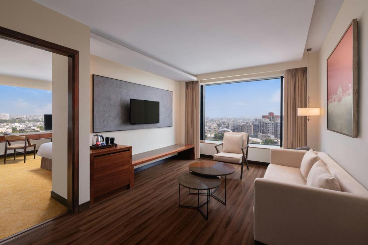 a living room with a couch and a tv at Renaissance Ahmedabad Hotel in Ahmedabad