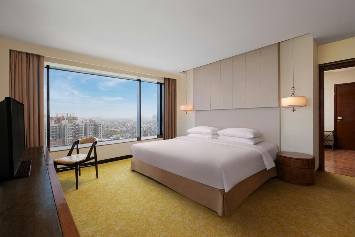 a bedroom with a large bed and a large window at Renaissance Ahmedabad Hotel in Ahmedabad