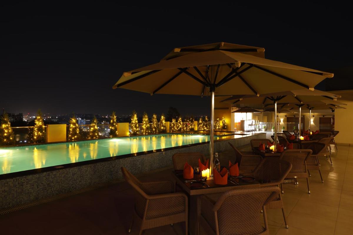 a patio with umbrellas and a swimming pool at night at Regenta Dehradun by Royal Orchid Hotels Limited in Dehradun