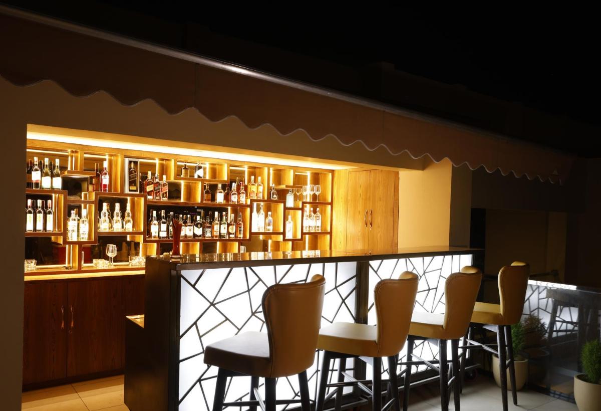 a bar with chairs and a shelf of bottles at Regenta Dehradun by Royal Orchid Hotels Limited in Dehradun