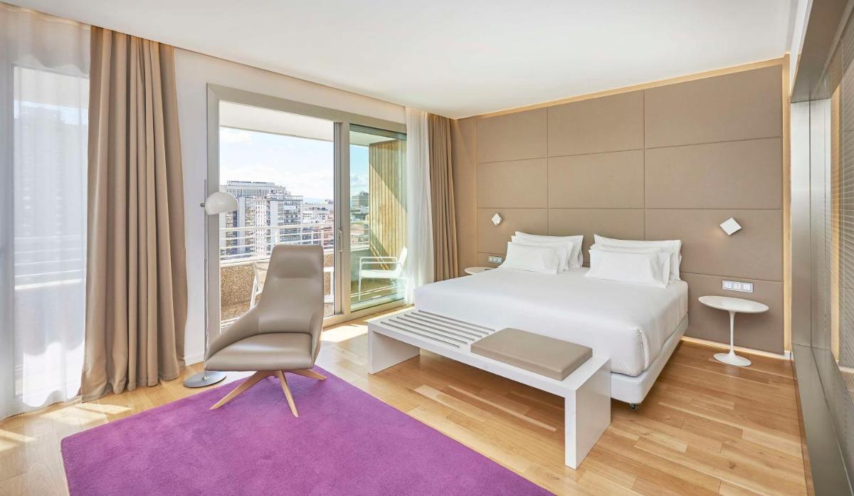 Un dormitorio con una cama blanca y una ventana grande. en NH Collection Madrid Eurobuilding, en Madrid