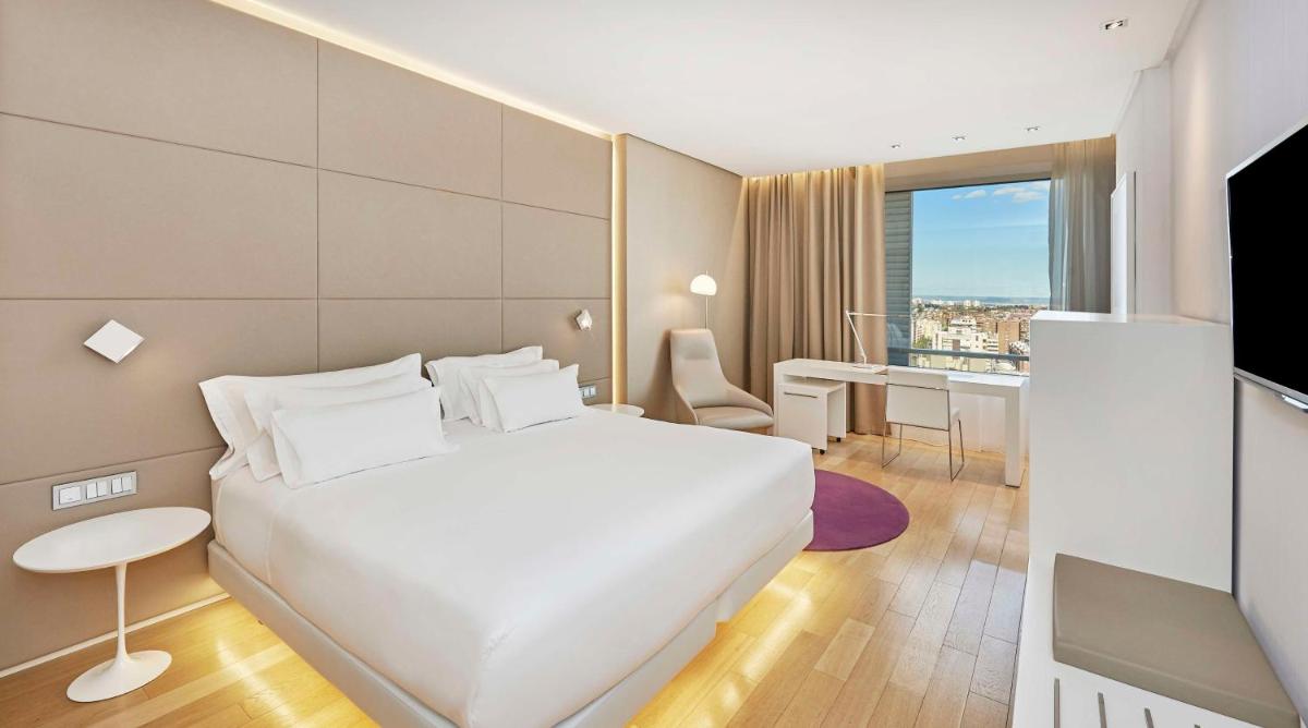 Una habitación de hotel con una cama blanca y un escritorio. en NH Collection Madrid Eurobuilding, en Madrid