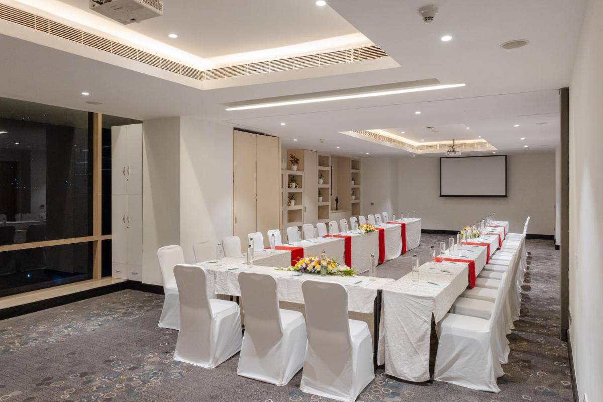 a room with a long table with white chairs and a screen at Holiday Inn Chennai OMR IT Expressway by IHG in Chennai