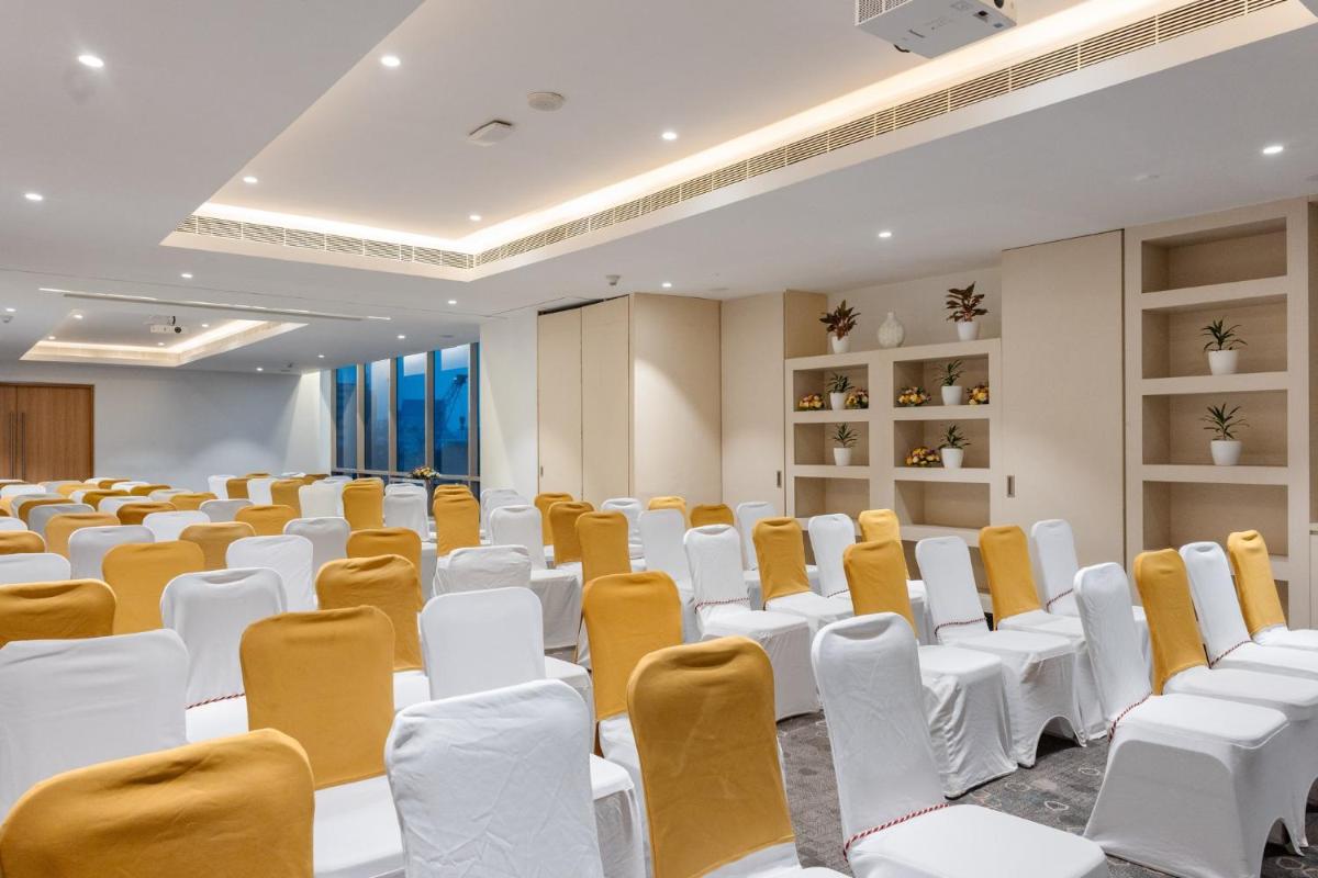 an empty room with white and orange chairs at Holiday Inn Chennai OMR IT Expressway by IHG in Chennai