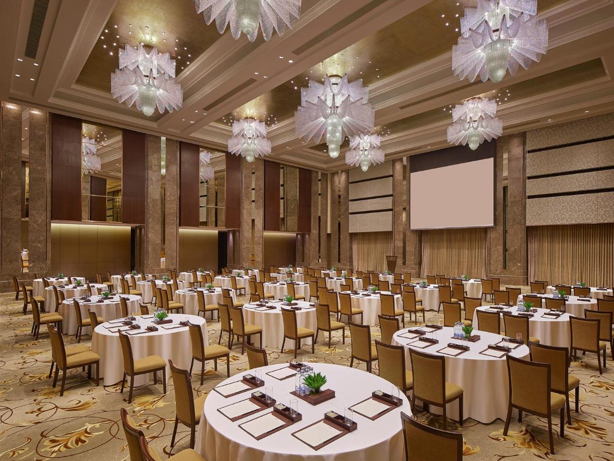 a banquet hall with tables and chairs and a screen at Shangri-La Bengaluru in Bengaluru a banquet hall with tables and chairs and a screen at Shangri-La Bengaluru in Bengaluru
