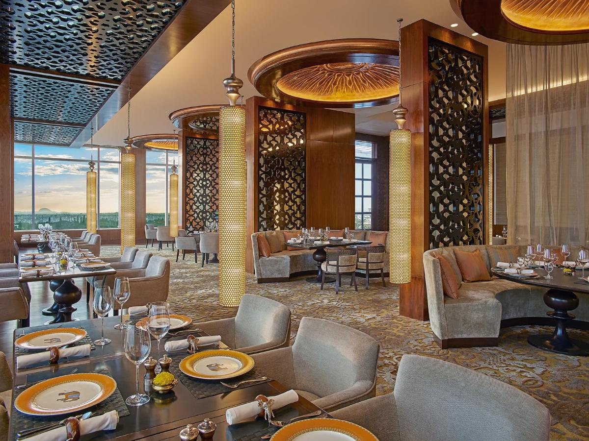 a restaurant with tables and chairs in a room at Shangri-La Bengaluru in Bengaluru a restaurant with tables and chairs in a room at Shangri-La Bengaluru in Bengaluru