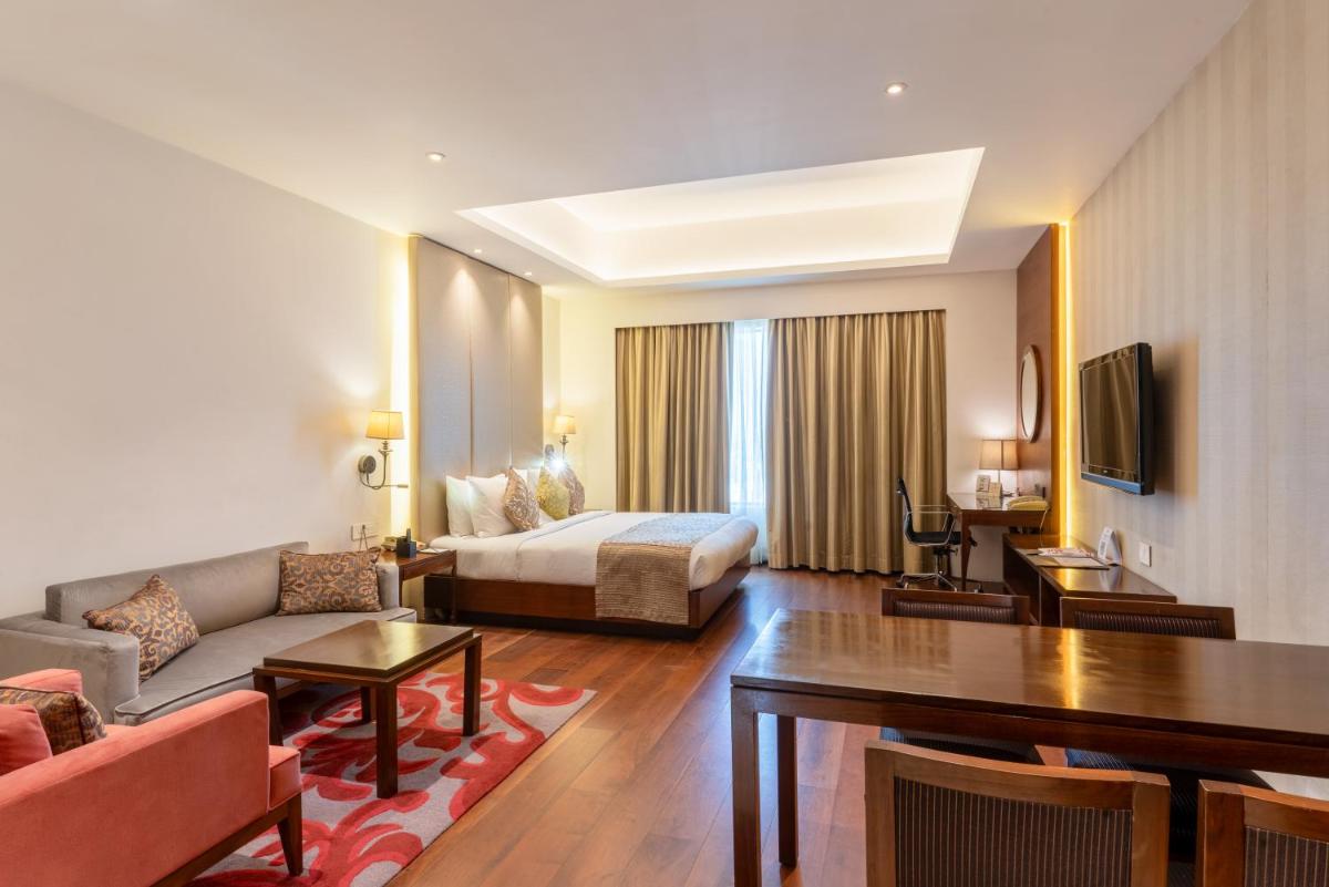 a hotel room with a bed and a living room at Pride Plaza Hotel, Kolkata in Kolkata